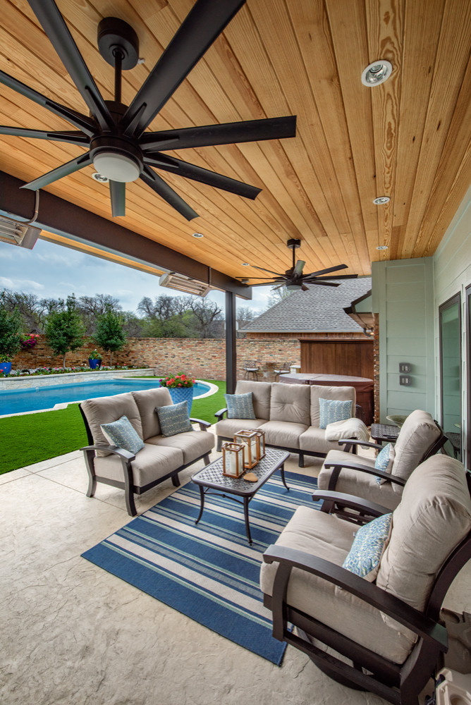 Outdoor patio area with ceiling fans, cushioned seating, and a view of a swimming pool